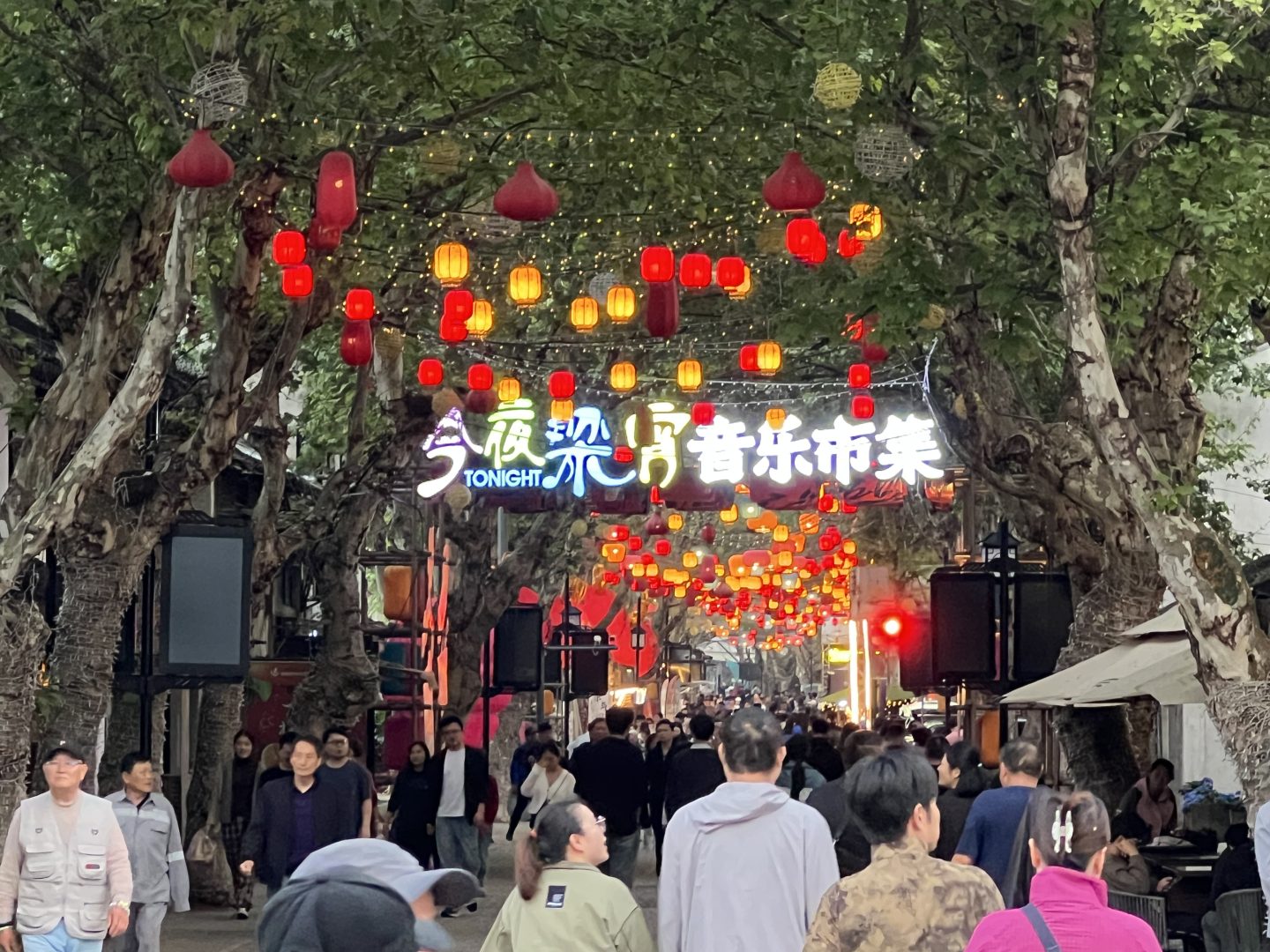 Un via di una città cinese affollata di persone con decori e lanterne