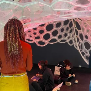 Partecipanti del Laboratorio della mostra Living Structures si sono raccolte/i sotto l’installazione Polythread di Jenny Sabin